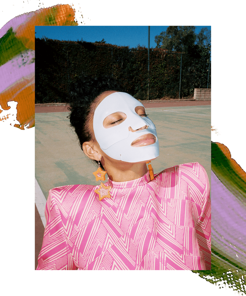 Model Lyric Mariah is wearing a sheet mask and sitting on the ground with her face turned up to the sky. She is wearing a pink striped top and orange star earrings. There is a decorative paint swatch of pink, purple, and green across the image.