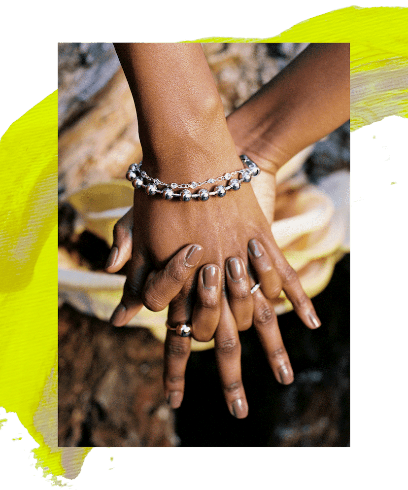 Hands interlocked wearing brown nail polish and a silver bracelet.