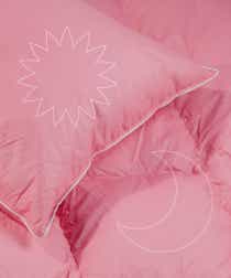 Pink pillow and bedding with line drawing over the top of a flower and a moon to represent day and night