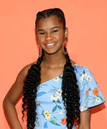 Marley Dias smiling wearing a blue floral dress with two cornrow braids.