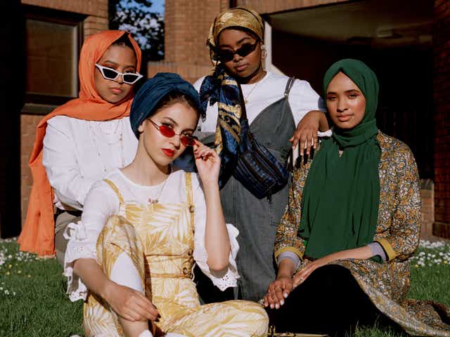 Portrait of stylish young Muslim women sitting on grass in front of building