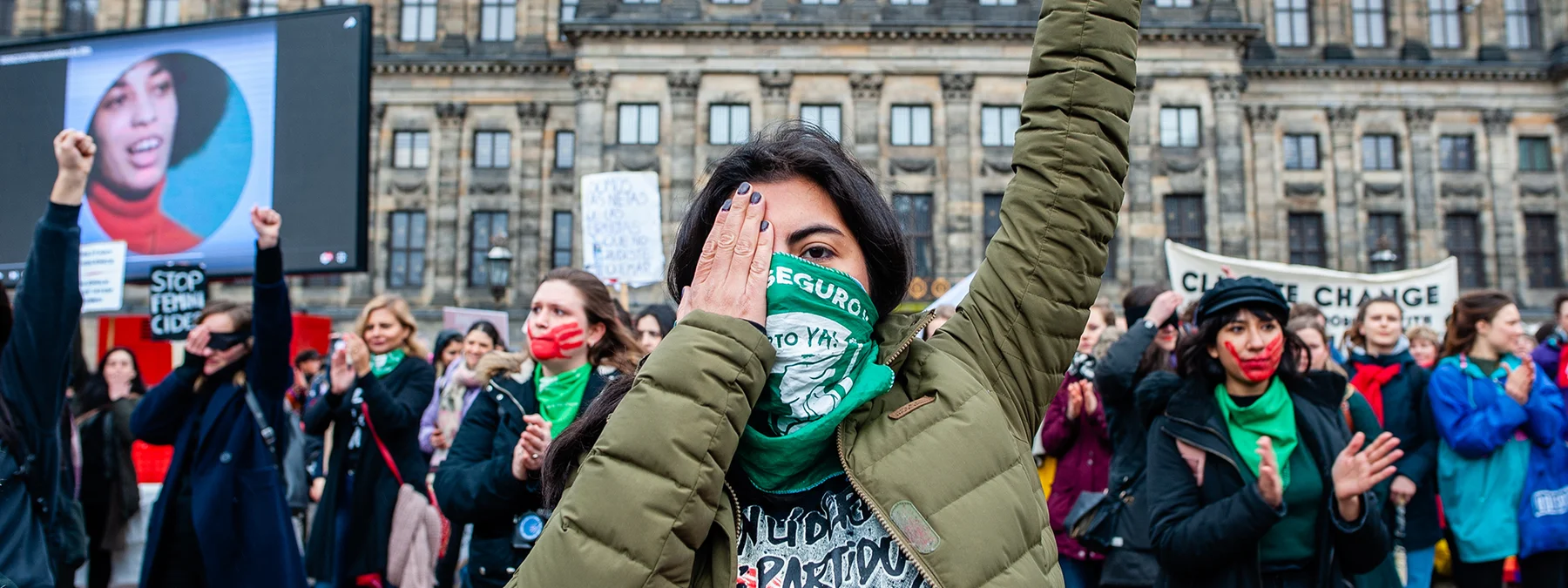Women with red hands painted on their faces and green scarfs are performing performing 'The Rapist is You' during the Women's march