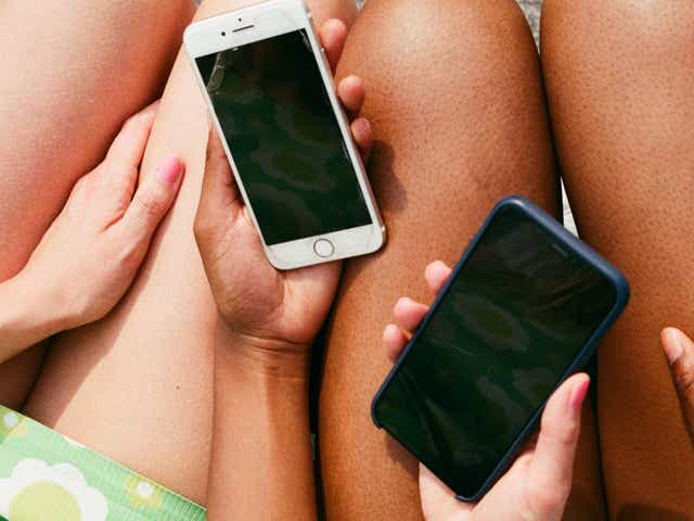Two phones in the hands of two women sitting side by side