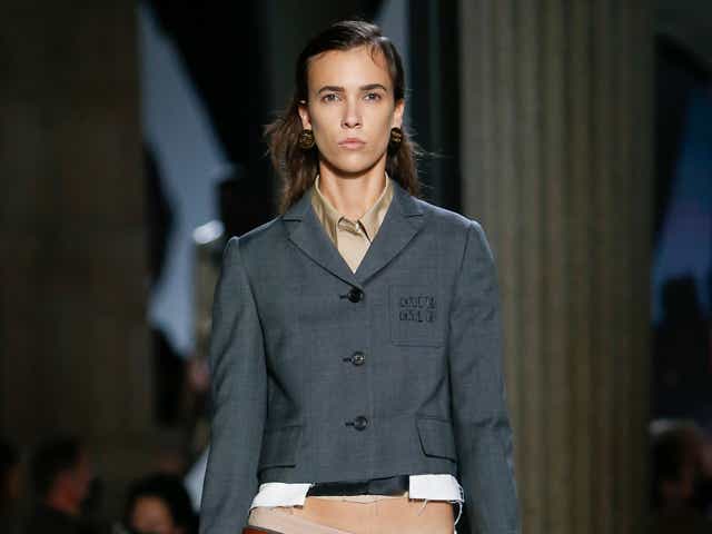 a model wears a grey blazer and mini skirt by miu miu