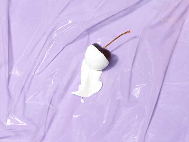 Cherry dipped in white paint on a purple background.