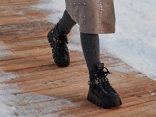 A model wearing black chunky platform hiking boots on the runway of Miu Miu show.