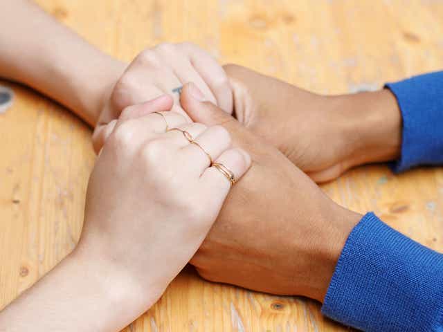 Close up of a couple holding hands over a wooden table