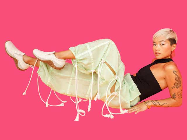 Photo of model wearing white Merrell shoes on pink backdrop