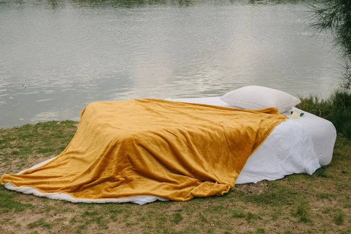 image of a squirt blanket placed on a bed next to a lake.