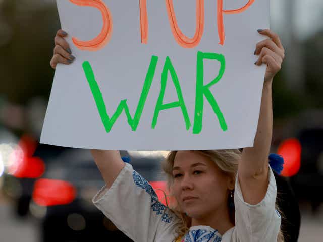 A woman holds a protest sign that reads 'Stop War'
