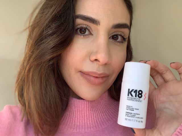 Selfie of Jacqueline wearing a pink jumper while holding K18 Leave-In Molecular Repair Hair Mask