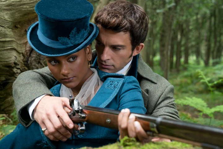 Simone Ashley and Jonathan Bailey in Bridgerton holding a gun in a hunting scene