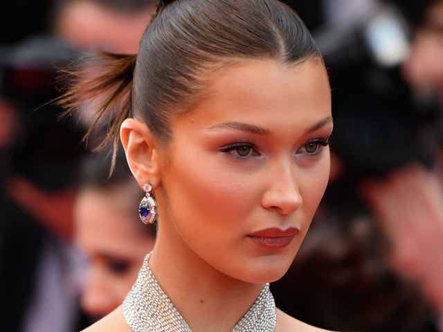 Bella Hadid porte un chignon plaqué, des boucles d'oreilles argentées et une robe argentée lors du 71e Festival de Cannes annuel en 2018.
