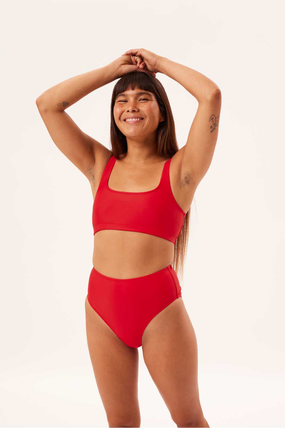 A model wearing the Girlfriend Collective Double Scoop Bikini in marina red. 