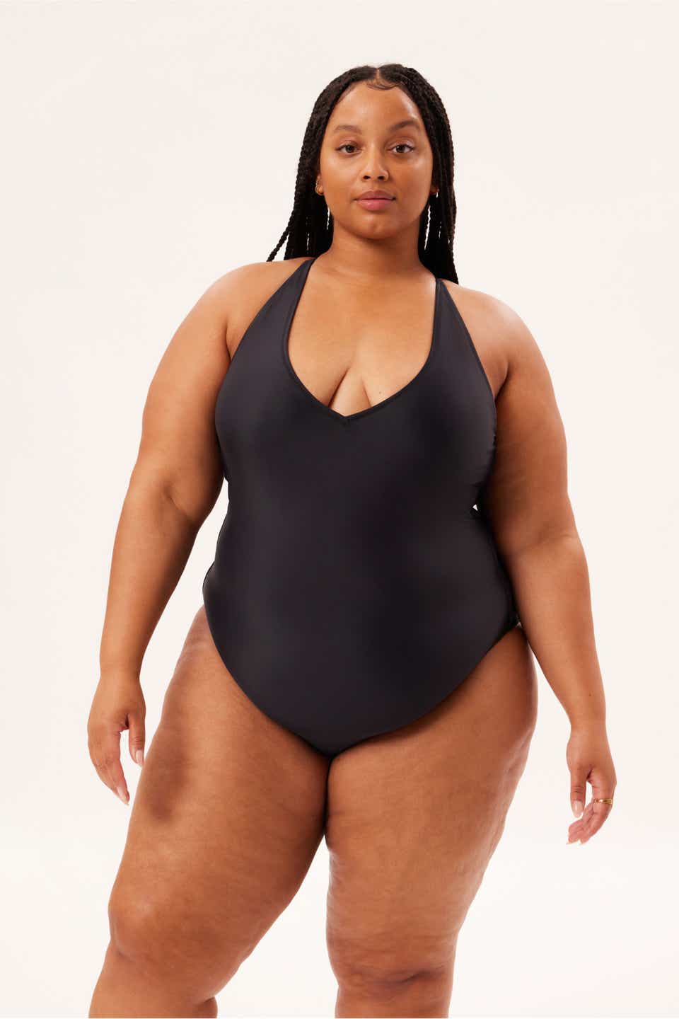 A model wearing the Girlfriend Collective Deep V-Neck One-Piece in black. 