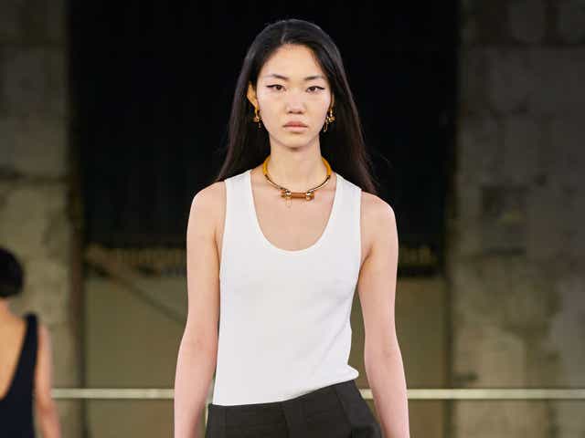 a model wears a white tank top and black pants at the bottega veneta fall 2022 show