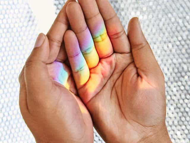 A person's hands shadowed with Pride colours