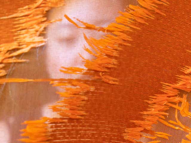 A person's face is concealed by orange fabric.