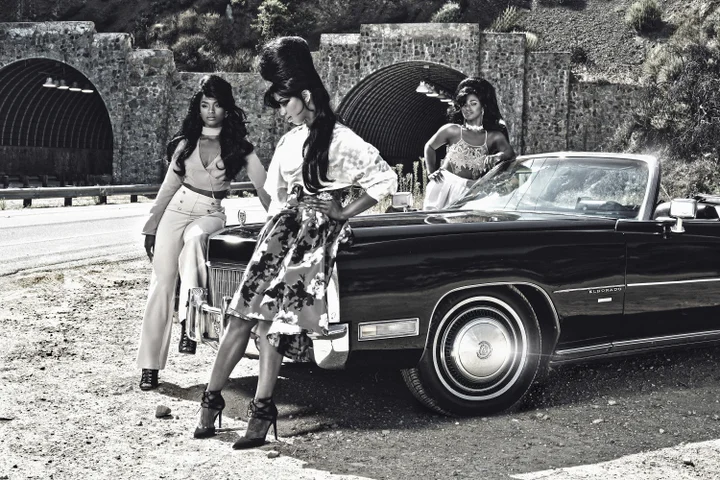 Three Black women leaning on an antique car