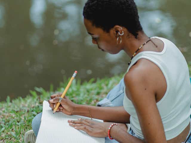 Woman spending time alone outdoors, writing on a notebook.