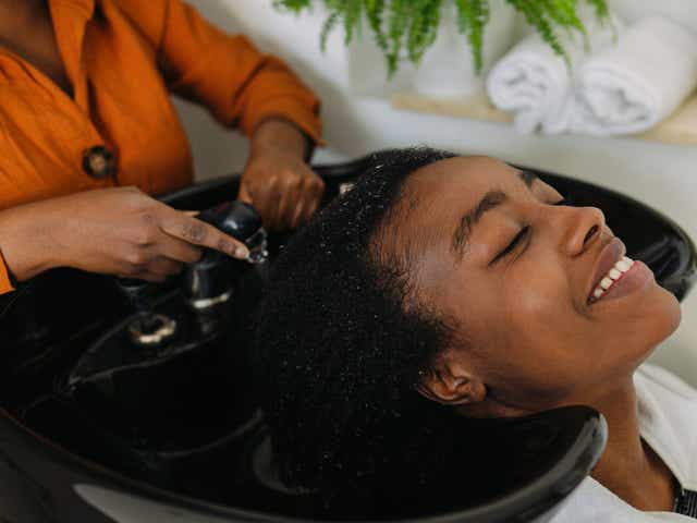 Photo of an African American hairdresser, washing hair to a customer with an Afro hair style