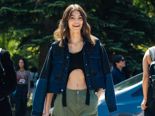 PARIS, FRANCE - JULY 05: Danish model Alberte Mortensen wears a blue jacket on her shoulders, black harness-style croptop, green cargo pants, green Fendi logo bag, and sneakers at the Chanel Fall/Winter 2022 Haute Couture show at L'étrier de Paris on July 05, 2022 in Paris, France. (Photo by Melodie Jeng/Getty Images)