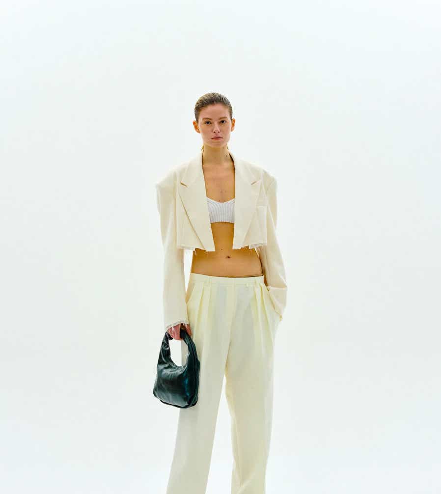a model wears a cropped white blazer and matching pants