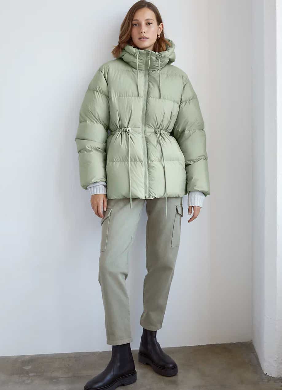 a model wears a green puffer coat with cargo pants and black boots from aritzia