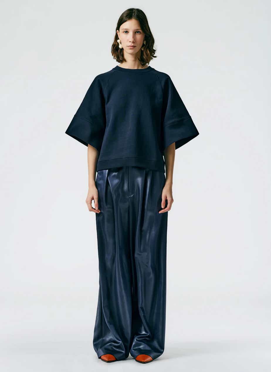 a model wears a navy sweater and leather wide leg pants from tibi