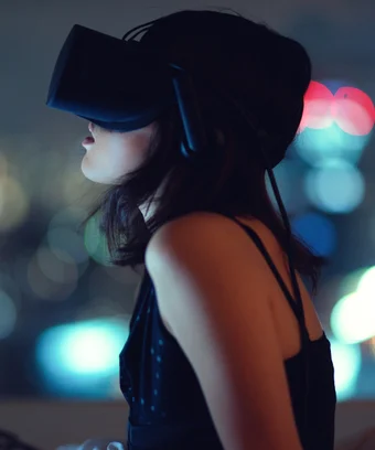 Woman using virtual reality headset at night with city lights in background
