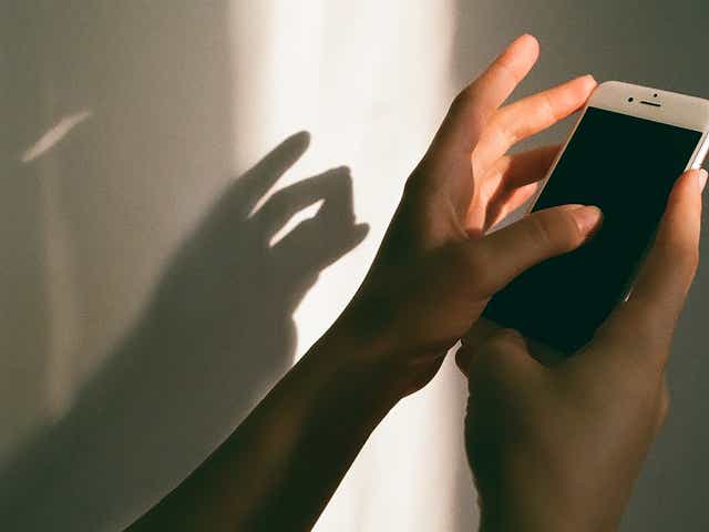 Hands holding a phone against a white shadowed wall