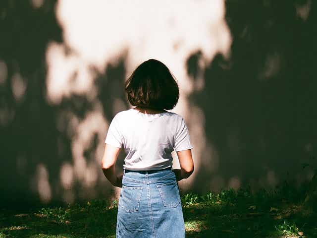 Back view of a woman looking at shadow cast on the wall.