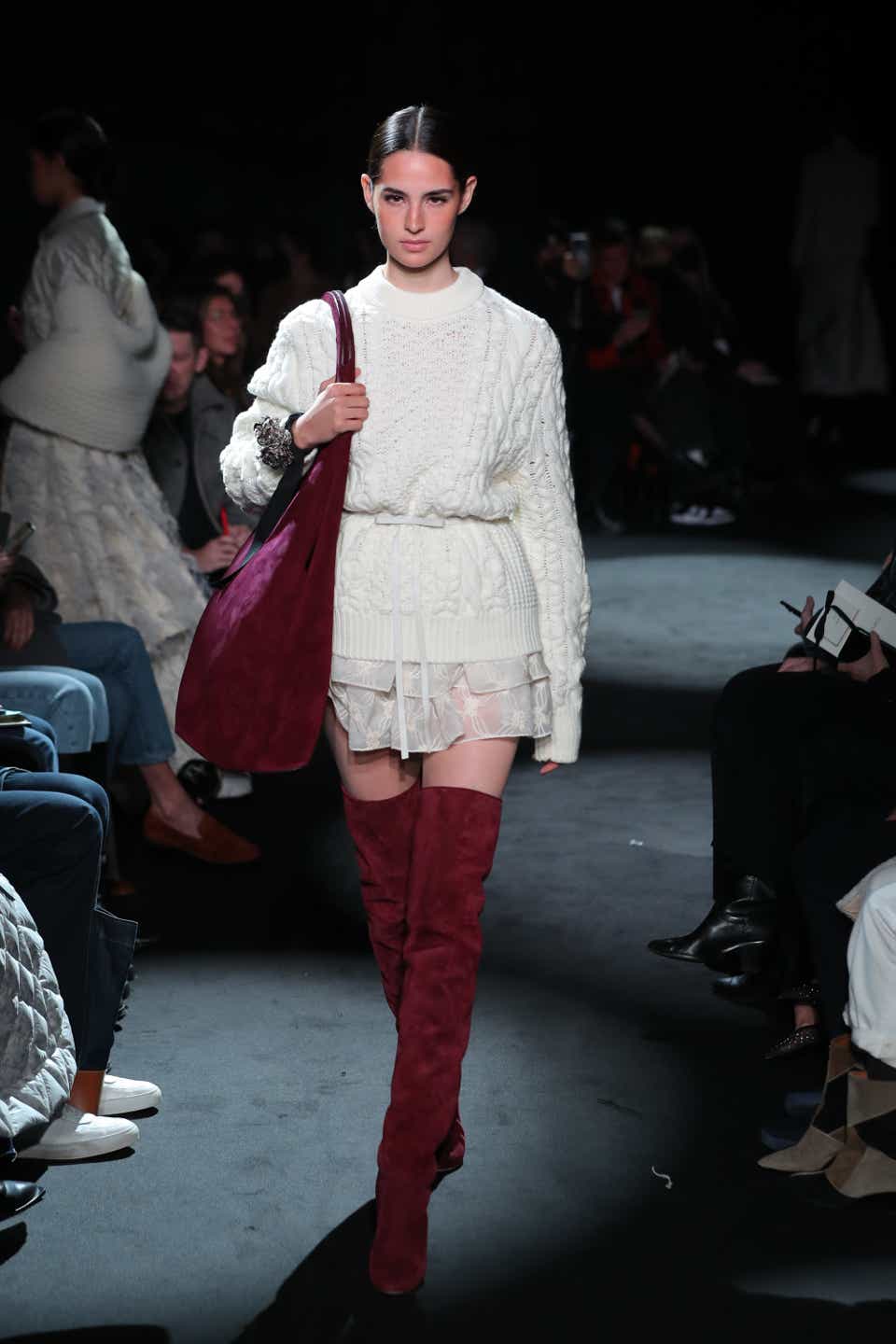 A model wearing a cable knit white sweater cinched at the waist at the Brandon Maxwell Fall 2022 runway.
