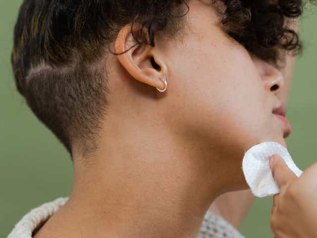 Woman cleansing her jawline with cotton pad