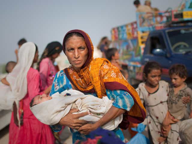 A woman displaced by flooding holds her newborn baby after having been evacuated by Pakistan Navy soldiers from their flooded village