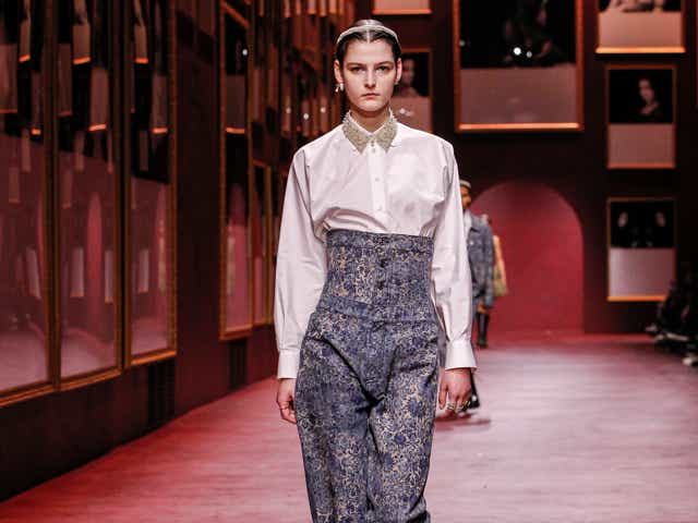 a model wears a white button-down shirt and corseted blue jeans from dior