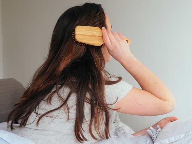 Woman photographed from behind while brushing her long brown hair