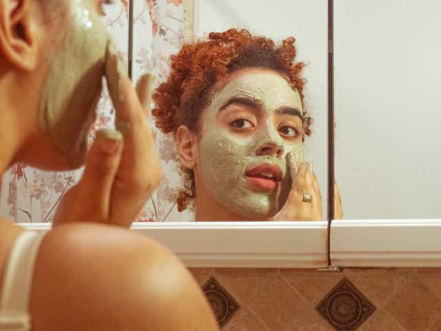 Person applying face mask and looking at the mirror