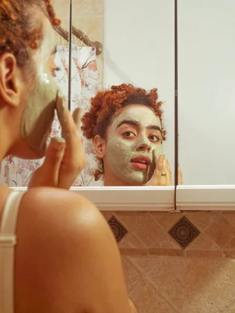 Person applying face mask and looking at the mirror