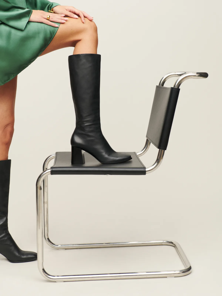 Diz boyu siyah çizme giyen bir model.