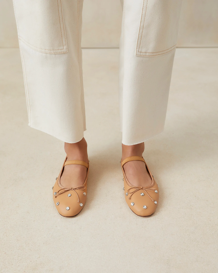 A model wearing caramel ballet flats.