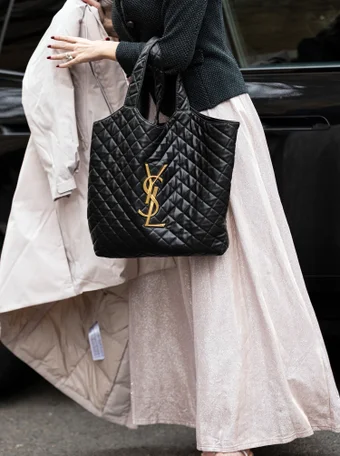 PARIS, FRANCE - JANUARY 25: A guest wears a black Yves Saint Laurent bag, outside Elie Saab, during Paris Fashion Week - Menswear Fall-Winter 2023-2024, on January 25, 2023 in Paris, France.