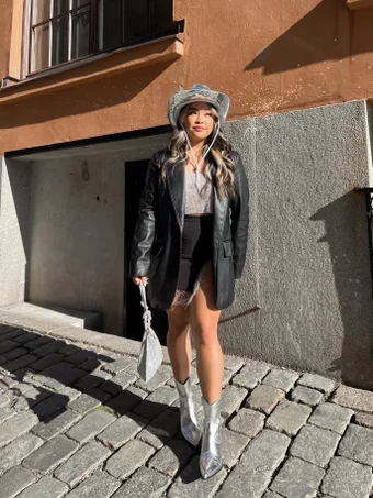 alliya bojador wears a disco mirrored cowboy hat with black leather blazer, silver crop top, black rihnestone fringed mini skirt and silver metallic cowboy hat