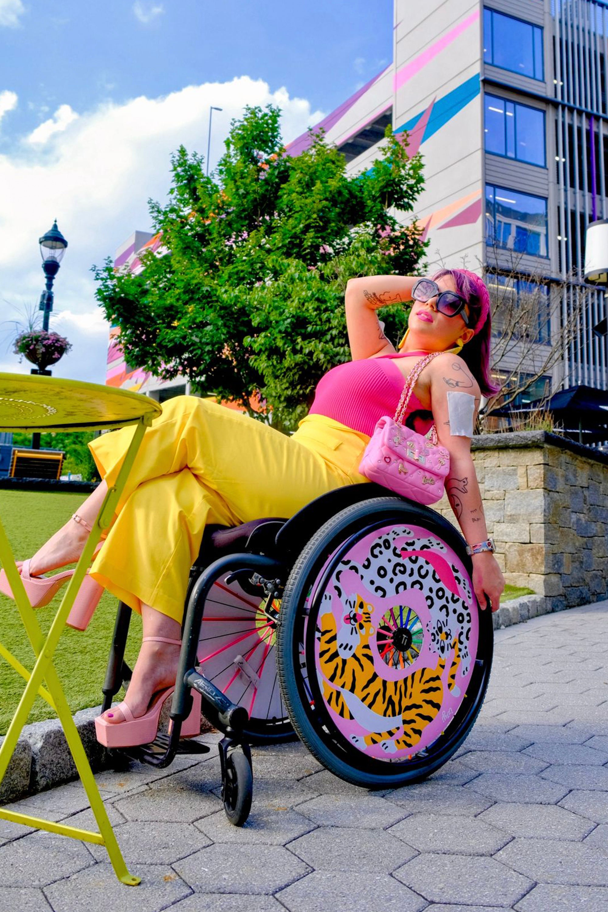 Seitenansicht einer behinderten Frau mit Schutzmaske, die mit Rucksack im  Rollstuhl sitzt und einen sonnigen Sommertag