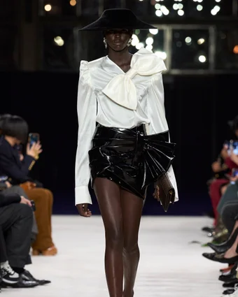 A model in a bow-adorned shirt and mini skirt at the Balmain show.