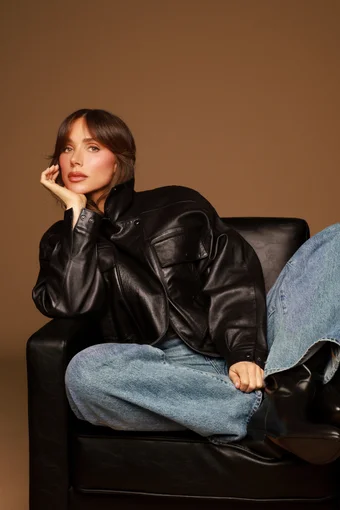 Makeup artist Mary Phillips in leather jacket and jeans on a leather chair