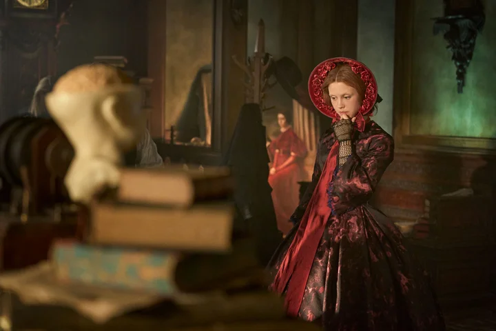 Mia Goth in a red dress and bonnet in Netflix's Frankenstein 2025.